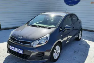 KIA Rio grise vue 3/4 avant droit, compacte 5 portes avec jantes alliage et plaque "OCCASION" visible.