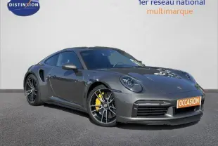 Porsche 911 Turbo S 3.7 essence gris métallisé vue 3/4 avant droit avec jantes noires et étriers jaunes.