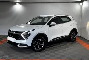 KIA Sportage blanc en 3/4 avant droit, avec signature lumineuse en forme de flèche et jantes noires distinctives.