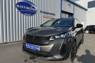 Peugeot 3008 gris en 3/4 avant droit, avec calandre noire et phares LED distinctifs, stationné devant un bâtiment.