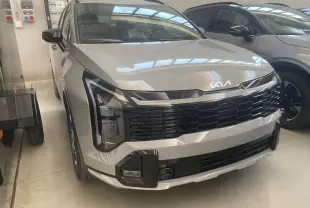 KIA Sportage Hybride gris lunaire vu de face 3/4 gauche, avec calandre noire et signature lumineuse verticale distinctive.