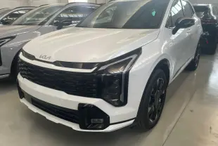 Vue 3/4 avant d'un KIA SPORTAGE hybride blanc 2026 avec calandre noire et jantes noires distinctives.