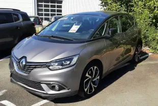 Renault Scenic IV gris cassiopée avec toit noir, vu en 3/4 avant droit sur parking extérieur ensoleillé.