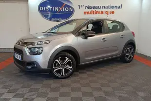Citroën C3 gris foncé vue 3/4 avant droit, avec phares LED et jantes alliage distinctives en intérieur showroom.