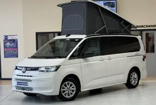Volkswagen California T7 blanc Candy en 3/4 avant avec toit relevable noir déployé en intérieur showroom.