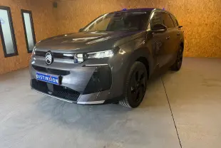 Vue 3/4 avant droite d'un Citroën C5 Aircross gris 2026 avec calandre moderne et jantes noires dans un garage.