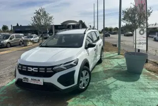 Vue 3/4 avant droite d'un Dacia Jogger blanc 2023 stationné, avec calandre noire et jantes simples.