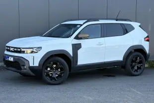 Dacia Duster Blanc Glacier en vue 3/4 avant droit, avec jantes noires et détails noirs contrastants sur les ailes.