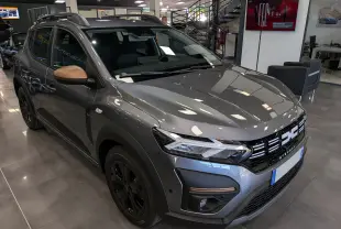 Vue 3/4 avant droite d'une Dacia Sandero Stepway TCe 110 Gris Schiste avec rétroviseurs couleur cuivre en showroom.