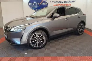 Nissan Qashqai gris foncé en 3/4 avant droit, avec jantes alliage et phares LED allumés, intérieur visible.