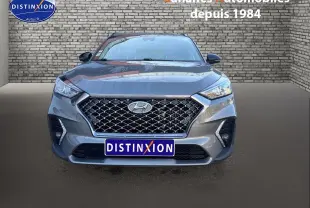 Vue frontale d'un Hyundai Tucson 1.6 Hybrid gris foncé avec calandre large et phares LED distinctifs.