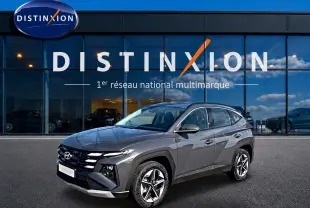 Hyundai Tucson gris ecotonic en 3/4 avant droit, avec jantes alu et calandre distinctive, devant showroom Distinxion.