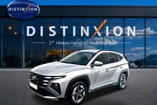 Hyundai Tucson gris shimmering en 3/4 avant droit, avec calandre noire et jantes alliage 18 pouces visibles.
