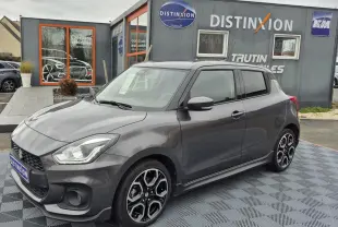 Suzuki Swift Sport gris minéral métal vue 3/4 avant droit, jantes alliage noires et détails sportifs visibles.