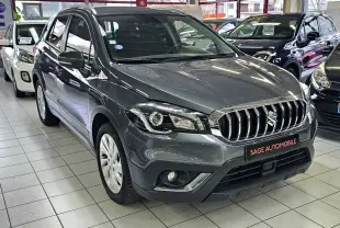 Suzuki SX4 S-Cross gris en 3/4 avant droit, avec calandre chromée et antibrouillards intégrés, en showroom.