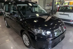 Volkswagen Caddy noir vue 3/4 avant droit en intérieur, avec phares LED et jantes alliage visibles.