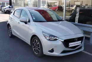 Vue 3/4 avant droite d'une Mazda2 blanche nacrée, avec jantes bi-ton et calandre noire brillante.