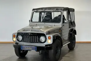 Suzuki Across LJ80 Cabriolet gris vu de trois quarts avant droit avec capote noire et phares allumés.