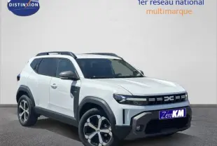Vue 3/4 avant droite du Dacia Duster blanc Glacier avec jantes alu et barres de toit noires visibles.