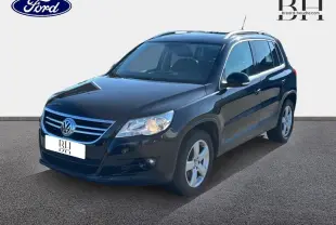Volkswagen Tiguan noir en 3/4 avant droit, avec jantes alu et phares allumés sur fond neutre.