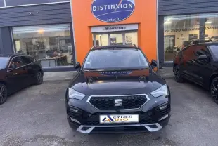 Vue avant d'un SEAT Ateca noir Magique Métal garé devant un concessionnaire avec calandre hexagonale chromée.