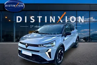 Vue 3/4 avant d'un Renault Captur gris rafale avec jantes noires et détails lumineux modernes, devant une vitrine Distinxion.