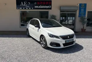 Peugeot 308 GT-Line blanche vue en 3/4 avant droit, avec jantes alliage et calandre noire distinctive.