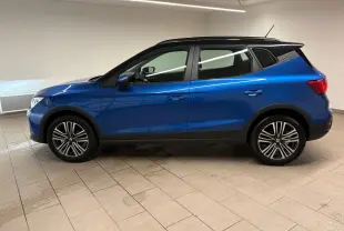 Vue de profil côté gauche du SEAT Arona 2025 en bleu saphir avec toit noir, soulignant ses jantes et lignes modernes.