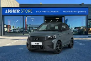Vue 3/4 avant d'une Ligier JS50 Elite Revo D+ gris graphite avec toit noir, stationnée devant un showroom Ligier.
