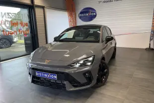 Vue 3/4 avant d'une CUPRA Leon gris magnétique avec jantes cuivrées et logo CUPRA sur le capot, en showroom.