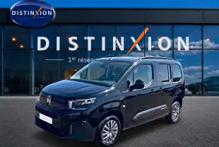 Citroën Berlingo noir vue 3/4 avant droit devant showroom Distinxion avec jantes alu et vitres teintées.