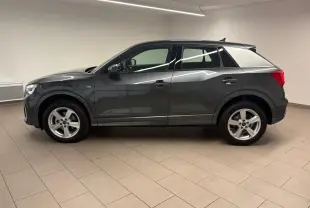 Audi Q2 35 TFSI S Line gris Daytona en profil gauche, avec jantes alliage et toit noir contrasté dans un intérieur neutre.