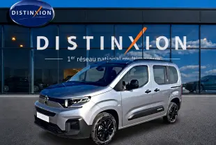 Citroën Berlingo Steel Grey en 3/4 avant droit, avec jantes noires et barres de toit visibles devant showroom Distinxion.