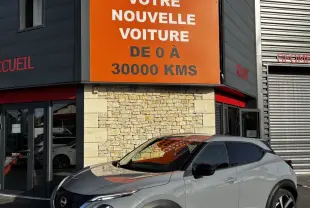 Nissan Juke Hybrid gris clair vue 3/4 avant droit, avec toit noir et jantes alliage distinctives.