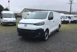 Vue 3/4 avant d’un FIAT Scudo Fourgon blanc 2024 avec pare-chocs noir et jantes tôles, stationné sur un sol gravillonné.