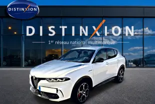 Vue 3/4 avant d'une Alfa Romeo Tonale blanche avec jantes spécifiques et calandre caractéristique, devant une vitrine Distinxion.