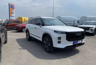SUV JAECOO J7 blanc khaki vu en 3/4 avant droit avec calandre verticale noire et jantes alliage 19 pouces.