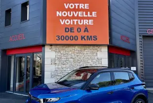 Citroën C3 100 BVM PLUS bleu vue 3/4 avant avec toit noir et jantes distinctives, devant un bâtiment commercial.