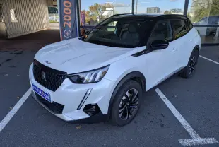 Peugeot 2008 GT blanc nacré en 3/4 avant droit, toit noir et jantes bi-ton visibles sur parking extérieur.