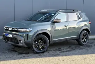 Vue 3/4 avant droit du Dacia Duster 2026 kaki lichen avec jantes noires et barres de toit noires.