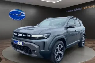 Vue 3/4 avant droit du Dacia Duster 1.8 Hybrid 155 Journey en gris schiste métallisé avec jantes bi-ton et calandre distinctive.