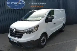 Renault Trafic Fourgon blanc en 3/4 avant droit, avec calandre noire et jantes acier, stationné devant un mur gris.