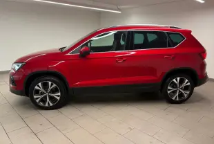 Vue de profil côté gauche d'un SEAT Ateca 2024 Rouge Velvet avec jantes alliage et toit ouvrant panoramique.