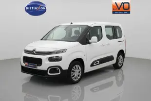 Citroën Berlingo blanc vue 3/4 avant droit avec protections latérales noires et barres de toit visibles.