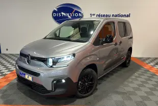 Citroën Berlingo Multispace gris Artense en 3/4 avant droit avec jantes noires et feux allumés en intérieur showroom.