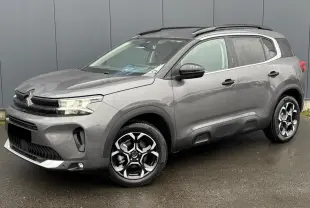 Vue 3/4 avant droit d’un Citroën C5 Aircross 2025 gris Platinium avec jantes alliage 18'' bi-ton et barres de toit noires.
