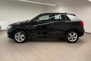 Audi Q2 35 TFSI S Line noir mythic vue de profil côté gauche dans un intérieur neutre, jantes alliage visibles.