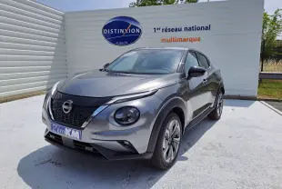 Nissan Juke Hybrid gris squale vu de 3/4 avant droit, avec calandre noire et jantes alliage modernes.
