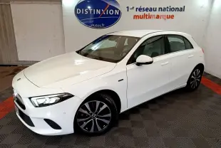 Vue 3/4 avant droite d'une Mercedes Classe A Berline blanche avec jantes noires et phares LED allumés.