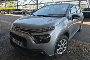 Citroën C3 gris Artense vue 3/4 avant droit, avec phares distinctifs et calandre chromée sous abri.